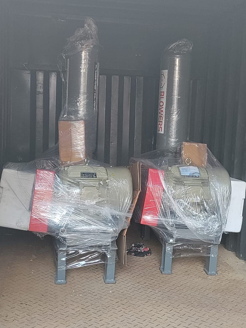 Pair of AEW root blowers wrapped in plastic inside shipping container